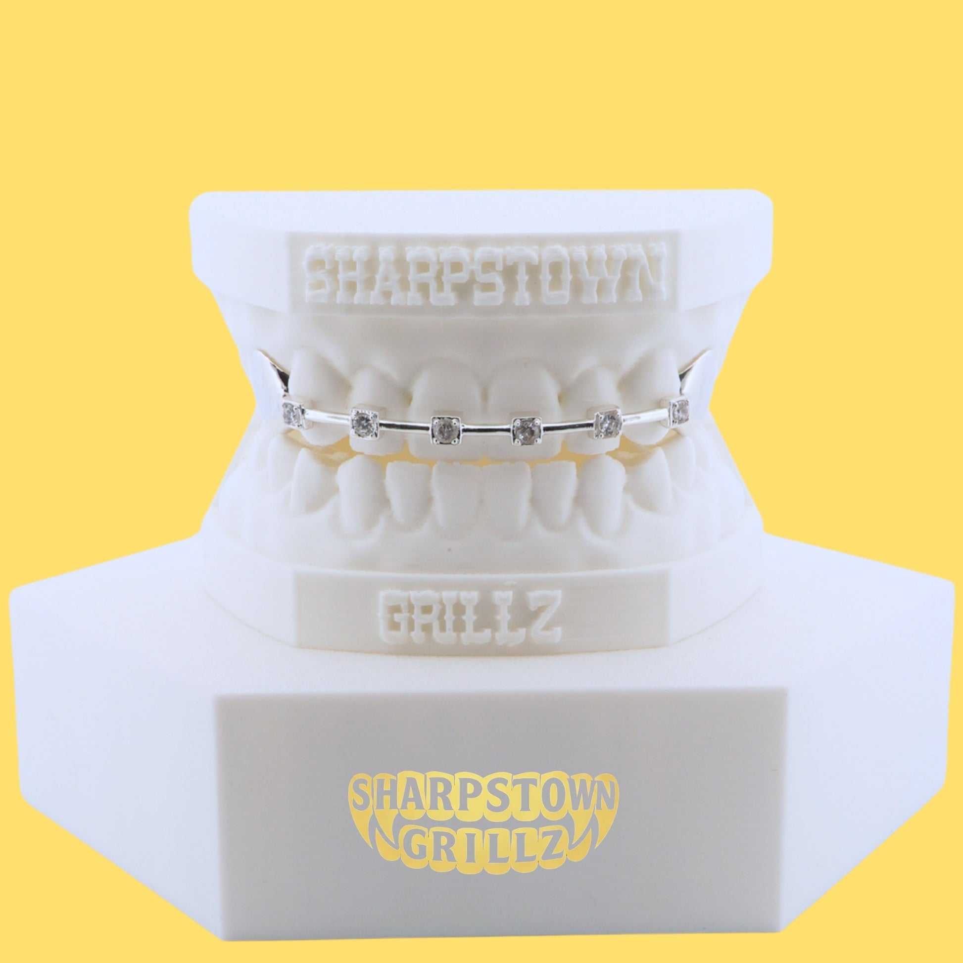Front view of custom silver bar grill with bezel-set stones and a solid side cap on dental cast.