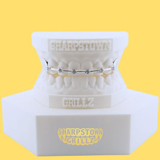 Front view of custom silver bar grill with bezel-set stones and a solid side cap on dental cast.