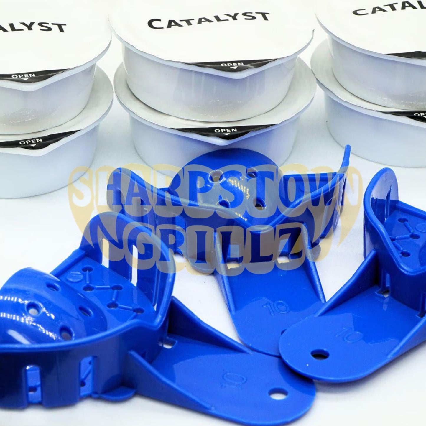 Blue plastic grill grates shown in the foreground with white foil-lidded canisters labeled 'CATALYST' and 'OPEN' in the background. A large semi-transparent 'Sharp Town Grillz' watermark overlays the center.