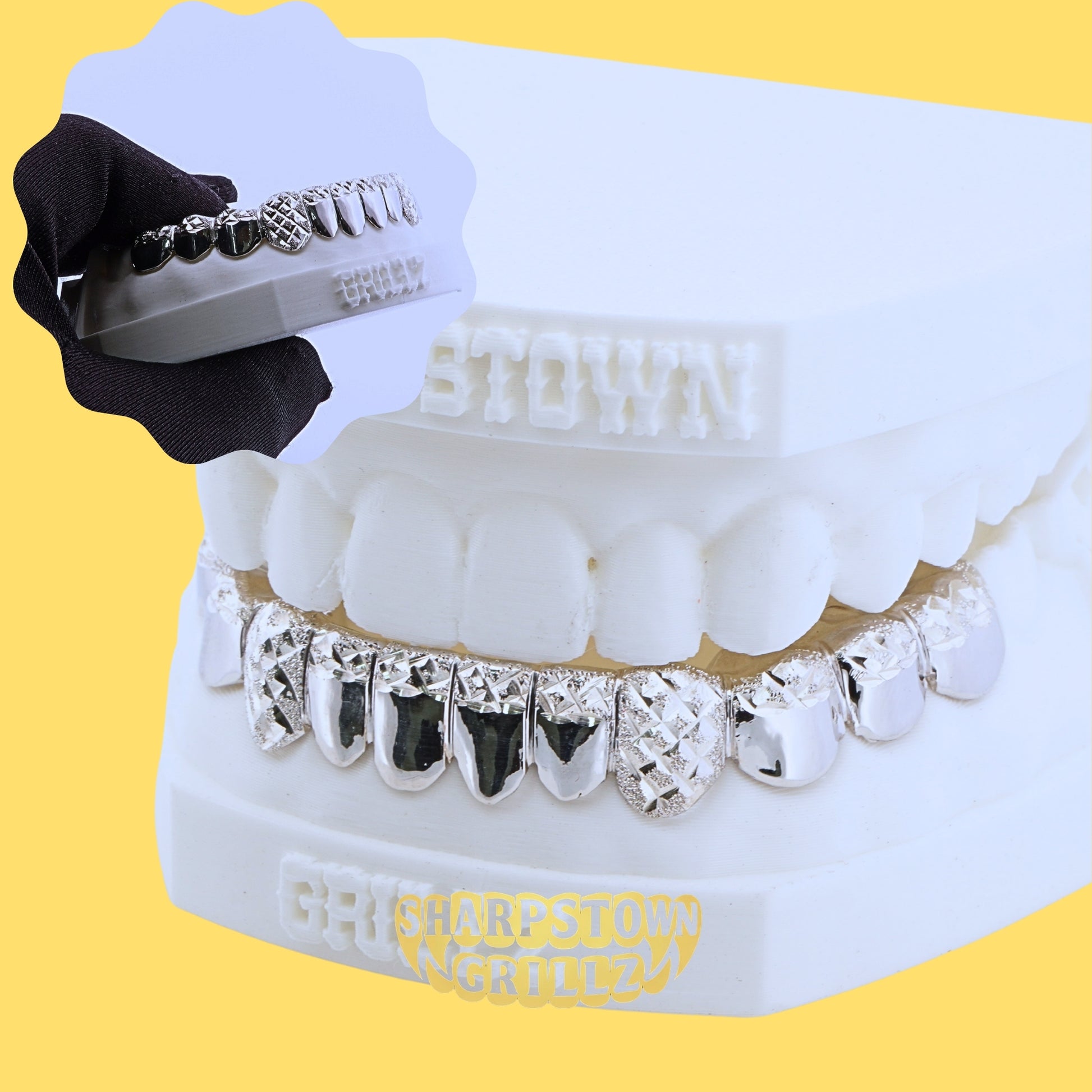Lower arch silver grillz featuring diamond cut textures and black enamel accents on yellow background.