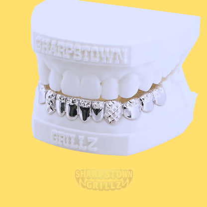 Silver bottom grill set with diamond dust faceting and black enamel filled center teeth on dental model.