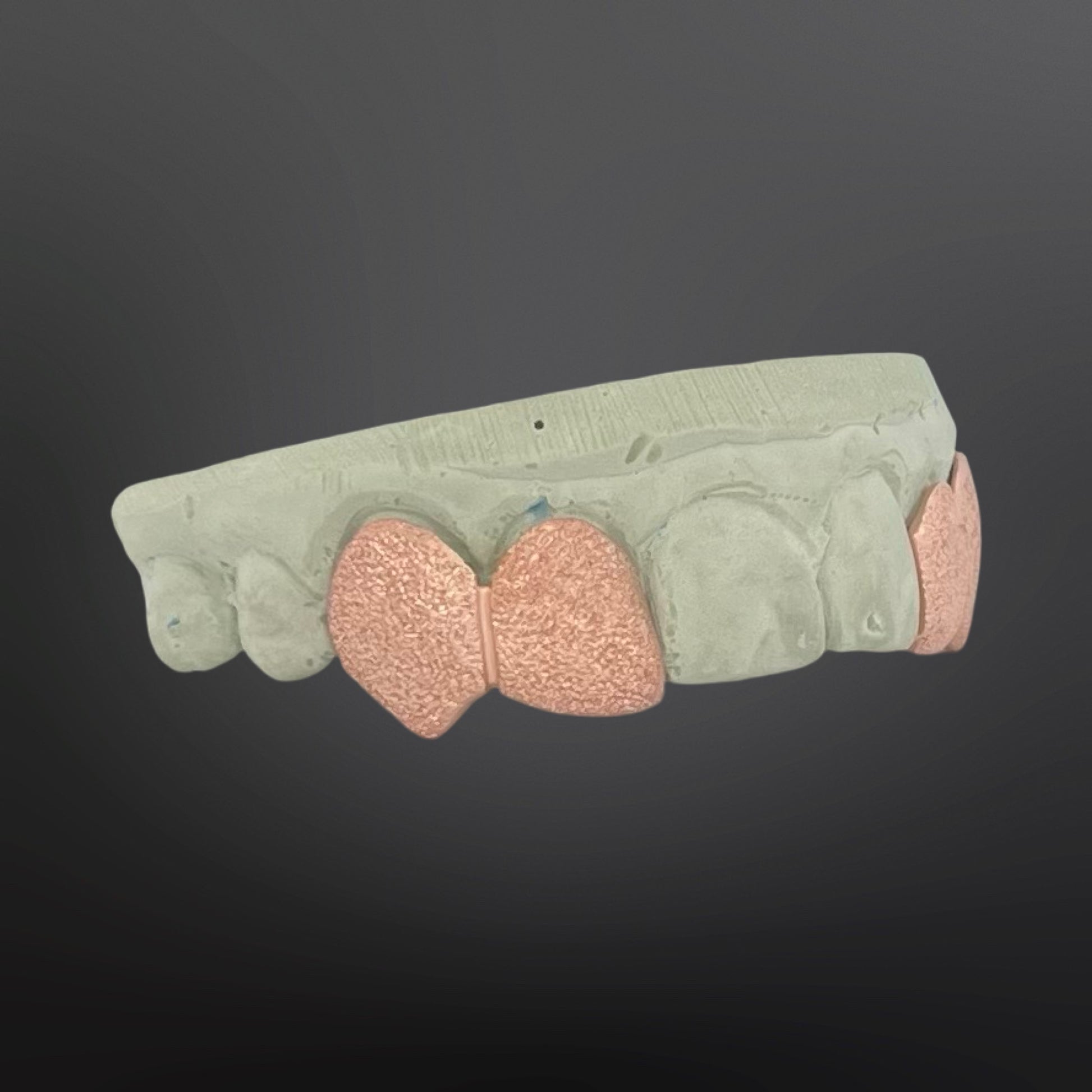 Ceramic mold with pink silicone inserts on a dark background