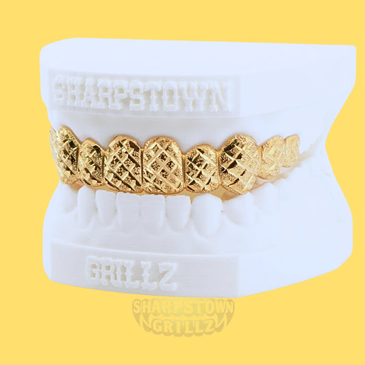 Front view of custom top gold grillz with laser diamond cut pattern and polished borders.