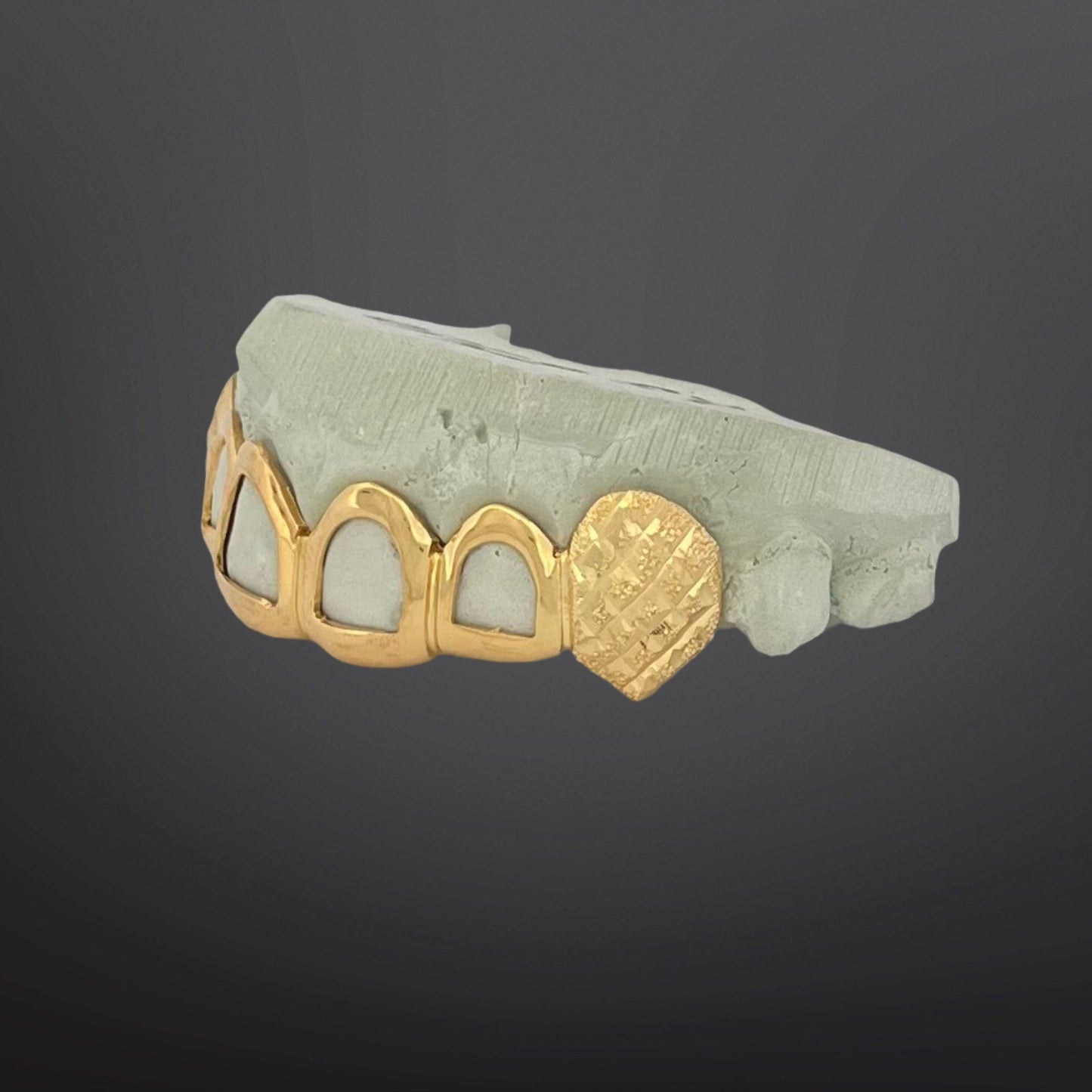 Gold grill on teeth with heart design on a gray background