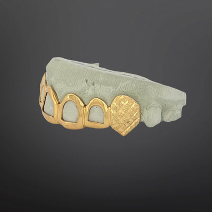 Gold grill on teeth with heart design on a gray background