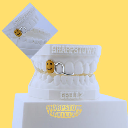 Yellow enamel smiley face tooth cap paired with open face wireframe grill on a 3D dental cast.