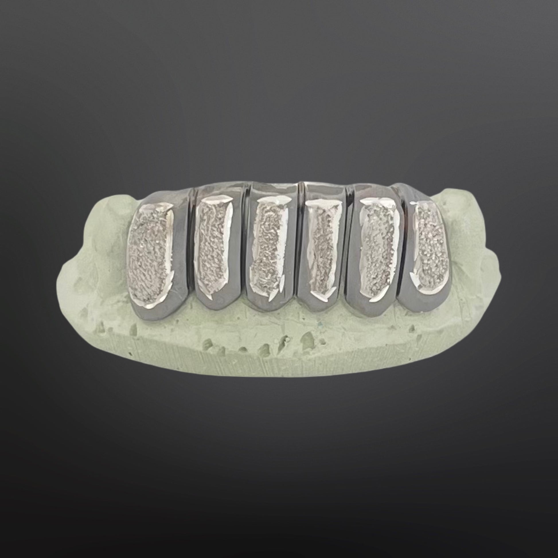 Dental model with metallic teeth on a dark background