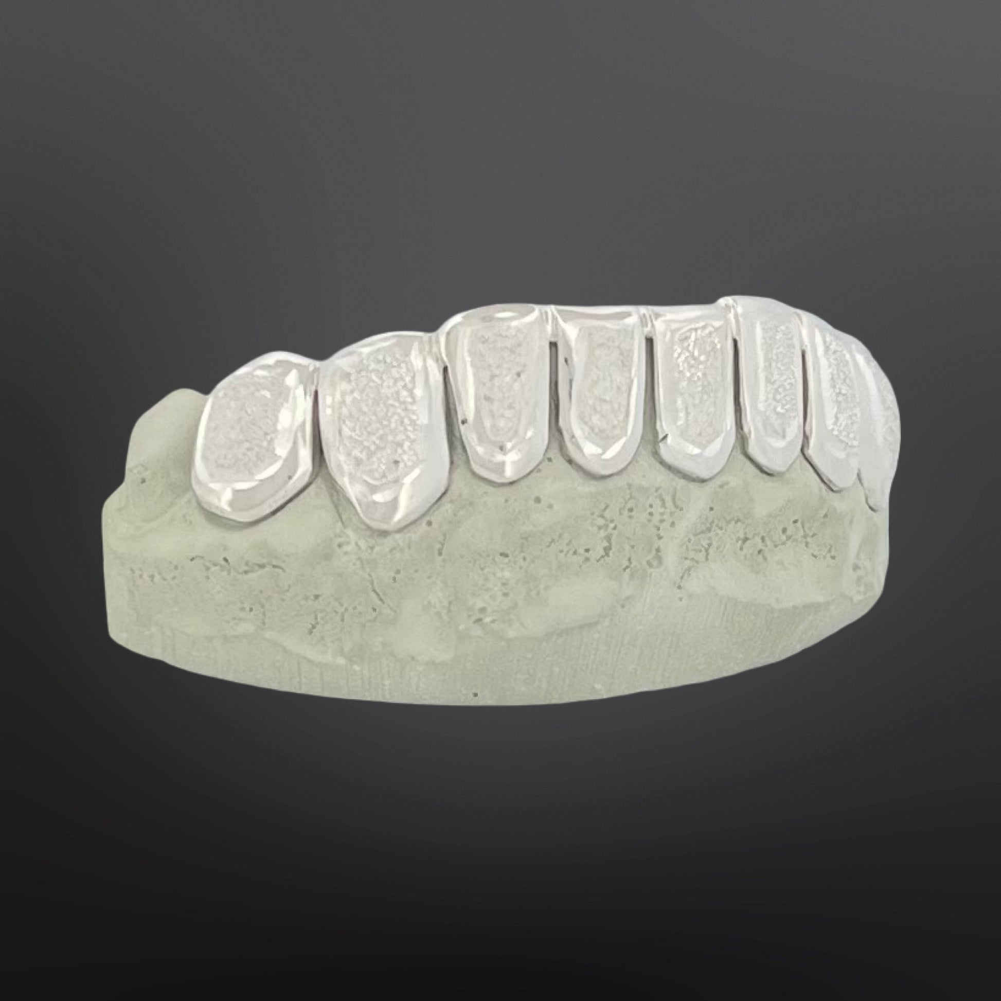 Dental model with metallic grill on a dark background