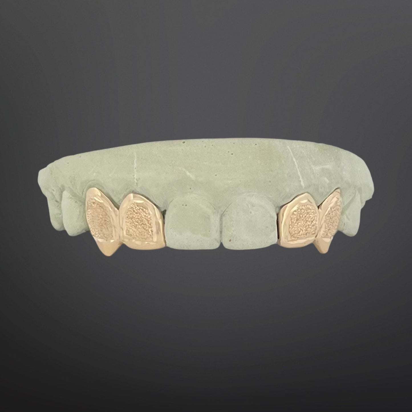 Green stone ring with gold butterfly accents on a dark background