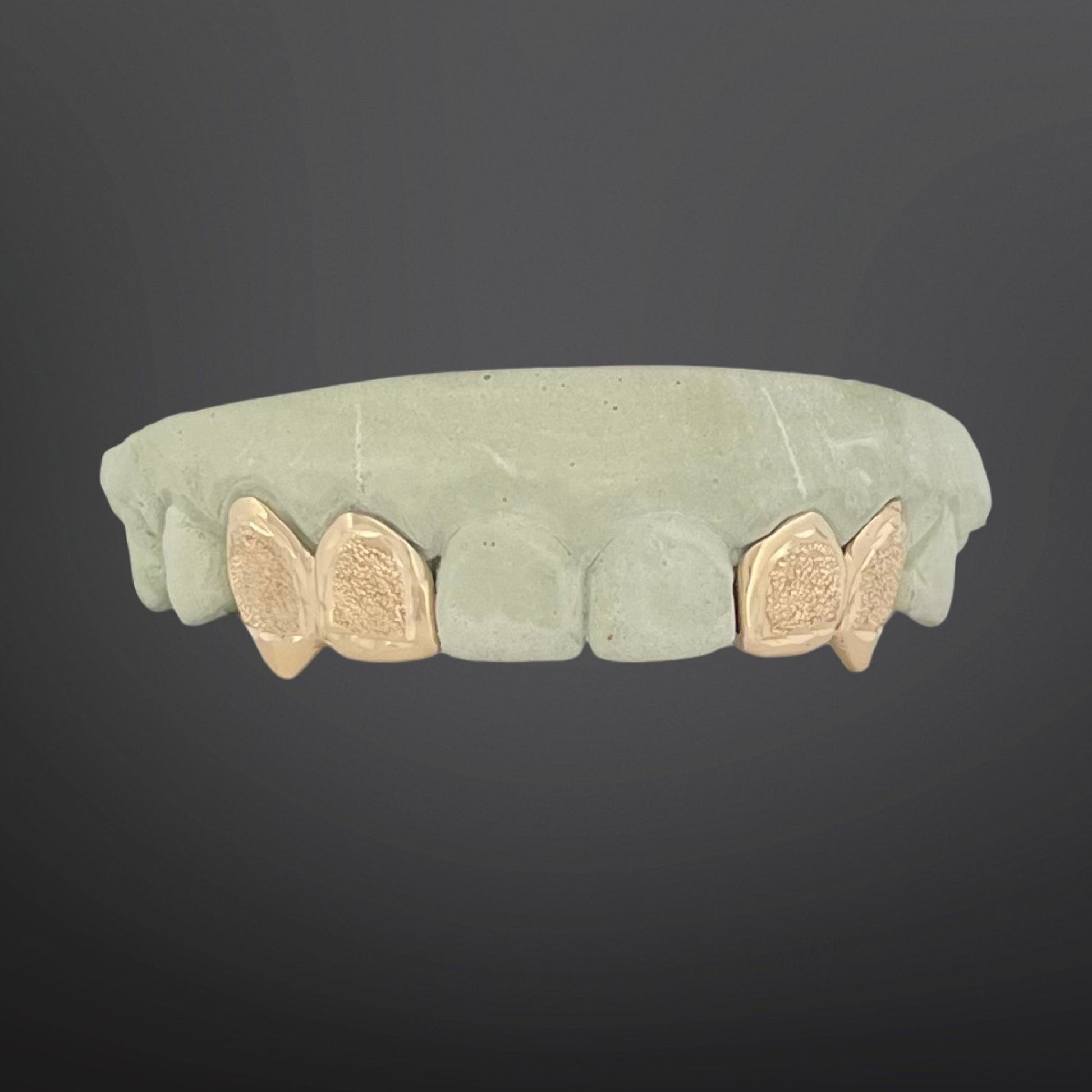 Green stone ring with gold butterfly accents on a dark background
