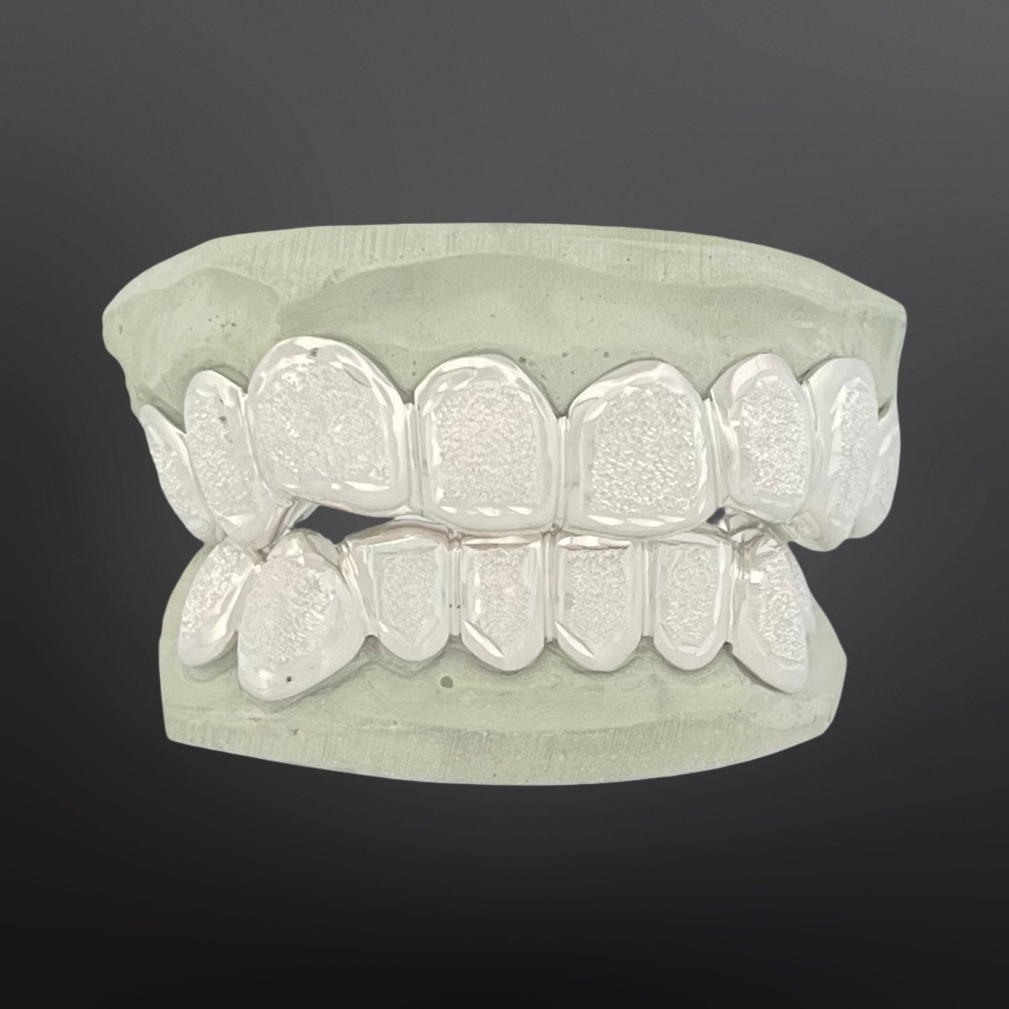 Silver dental grillz on a gray background