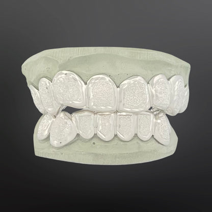 Silver dental grillz on a gray background