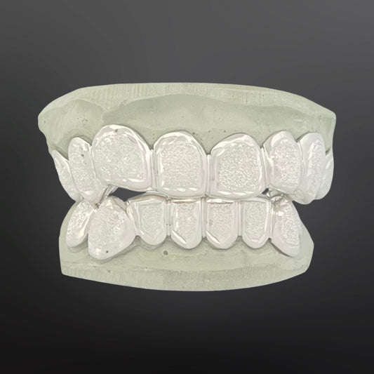 Silver dental grillz on a gray background