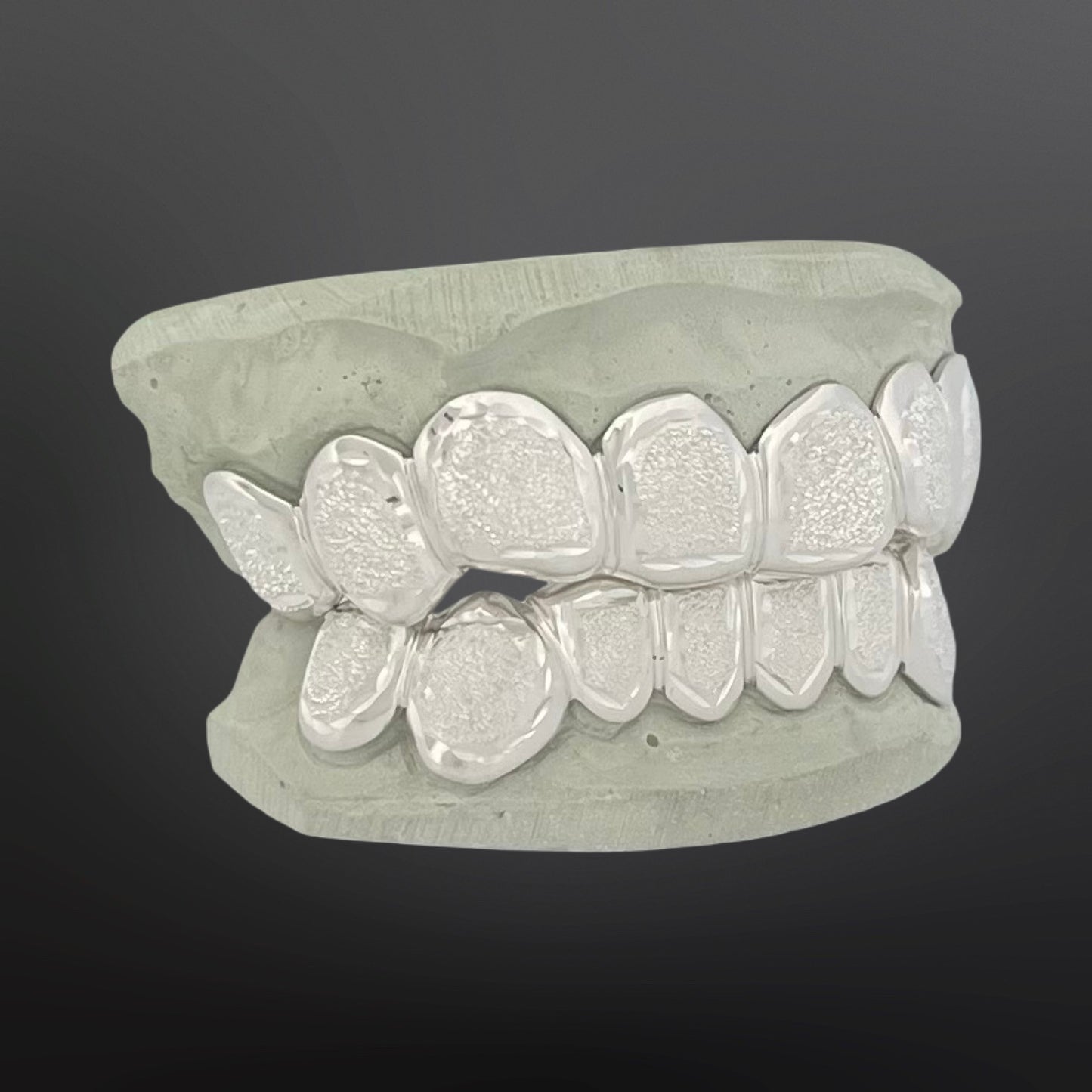 Silver dental grill on a gray background