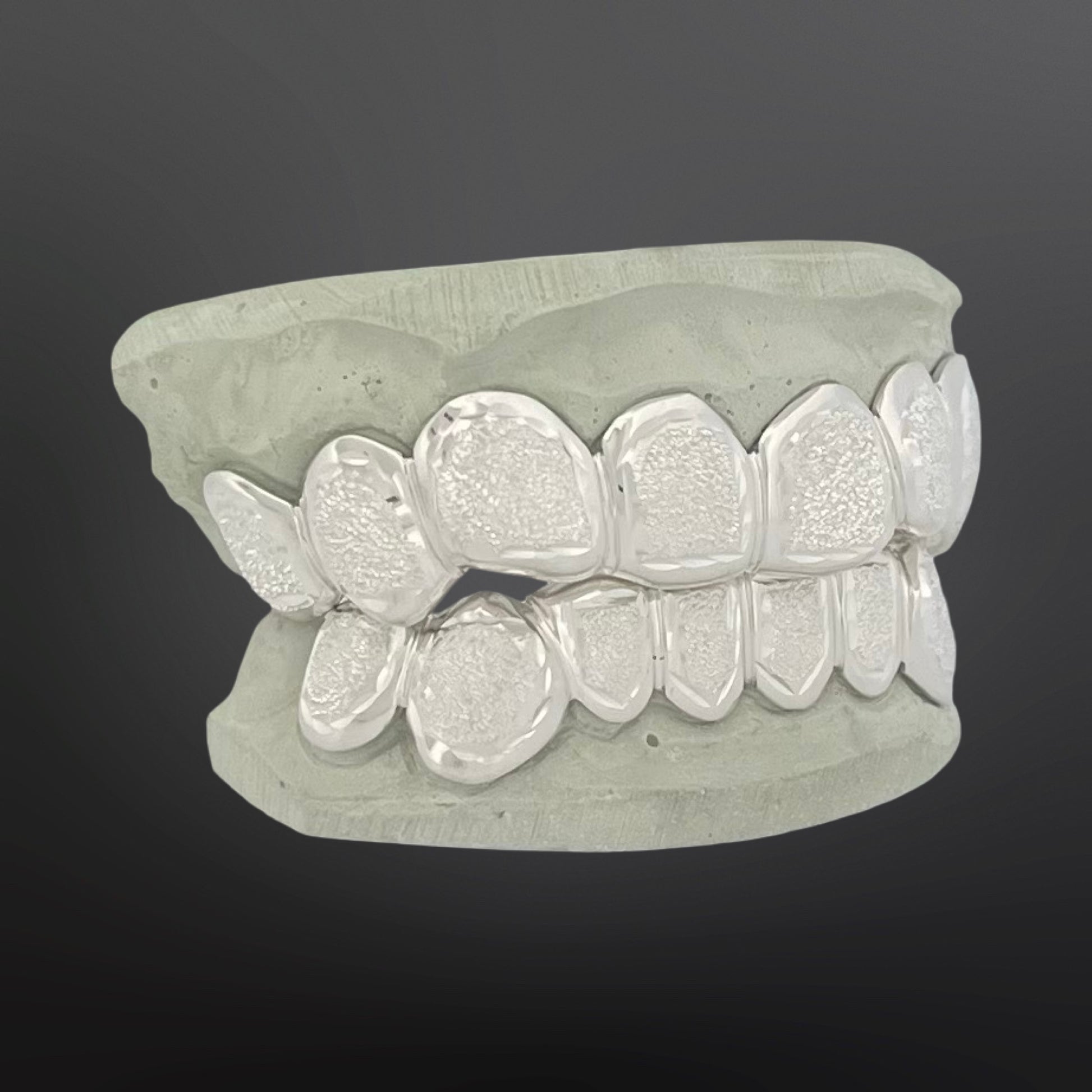 Silver dental grill on a gray background