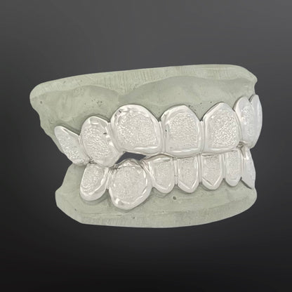 Silver dental grill on a gray background